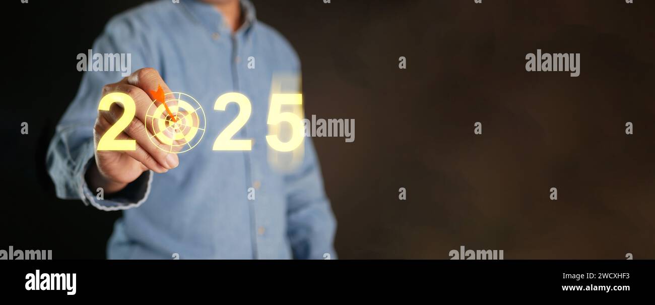 Buon anno 2025. Un uomo con uno stilo tocca l'anno che cambia nel 2025 con un tabellone per impostare e concentrarsi sul nuovo obiettivo per il nuovo te Foto Stock