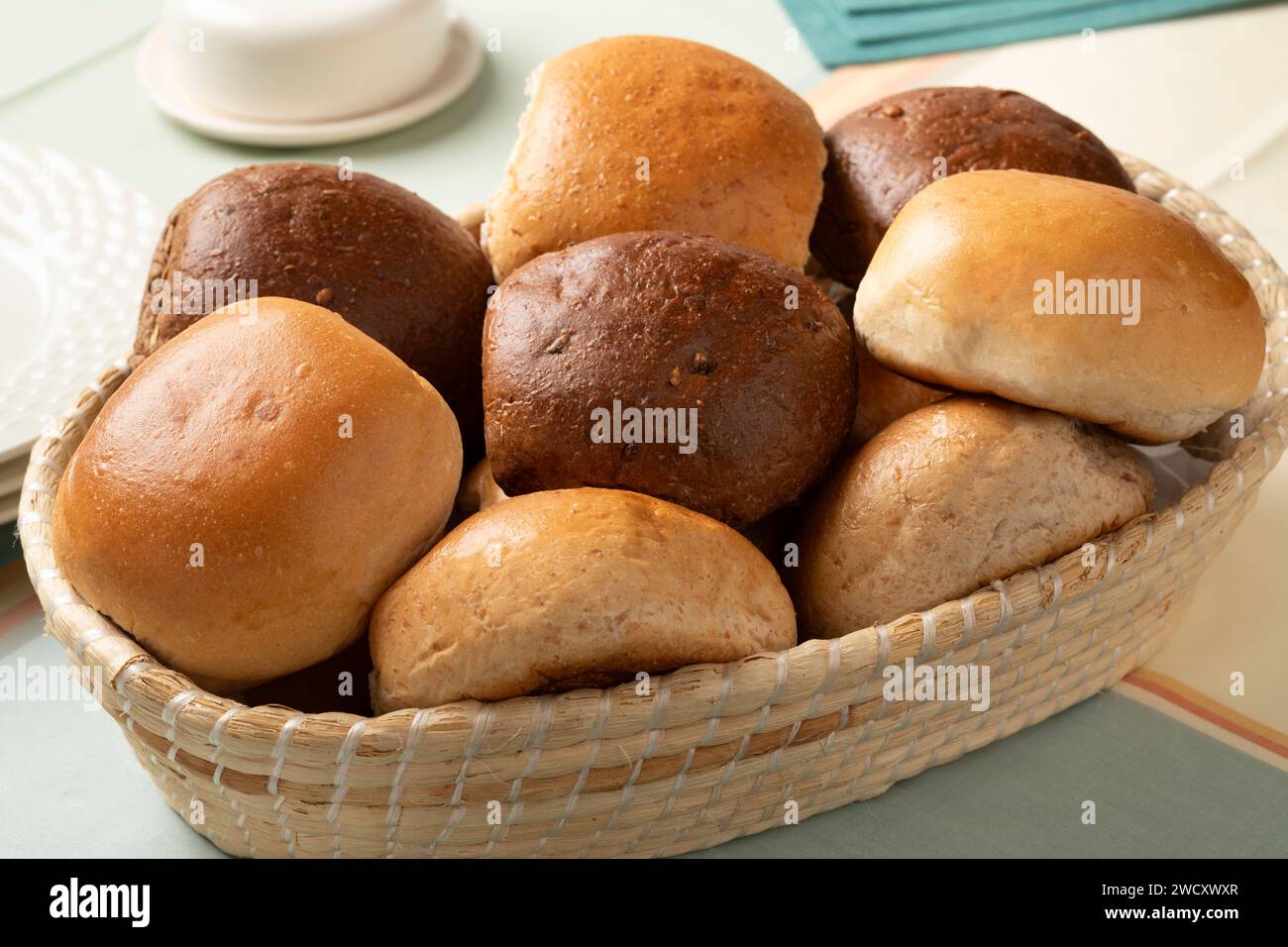 Cestello con una variante di panini bianchi e marroni appena sfornati in primo piano sul tavolo Foto Stock