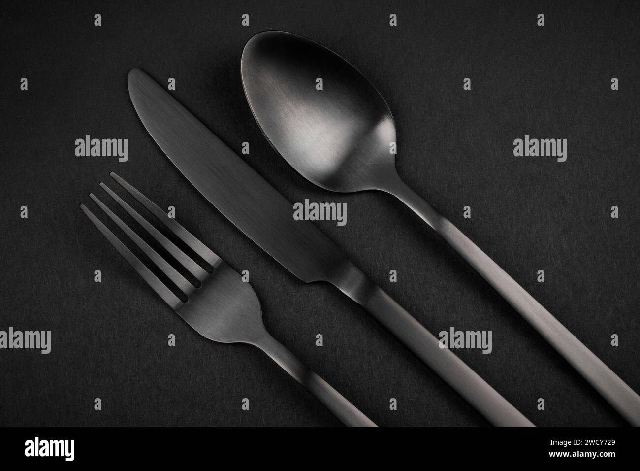 Set argenteria nera. Forchetta, coltello e cucchiaio su sfondo nero Foto Stock