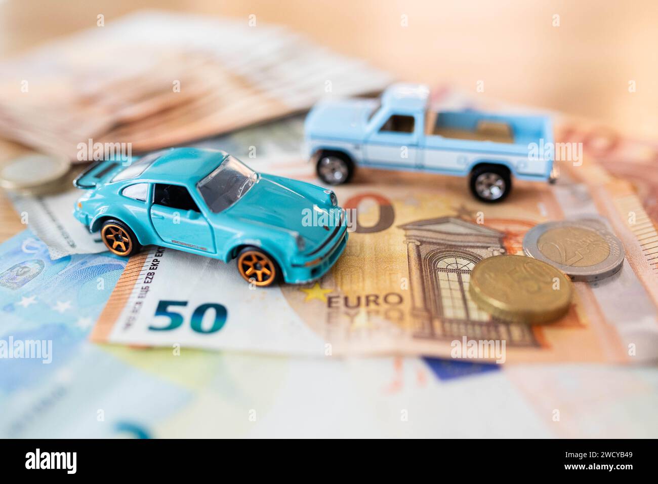 Macchinine giocattolo in euro, composizione di natura morta, simbolo di spese elevate per la mobilità privata con un bilancio familiare. Foto Stock