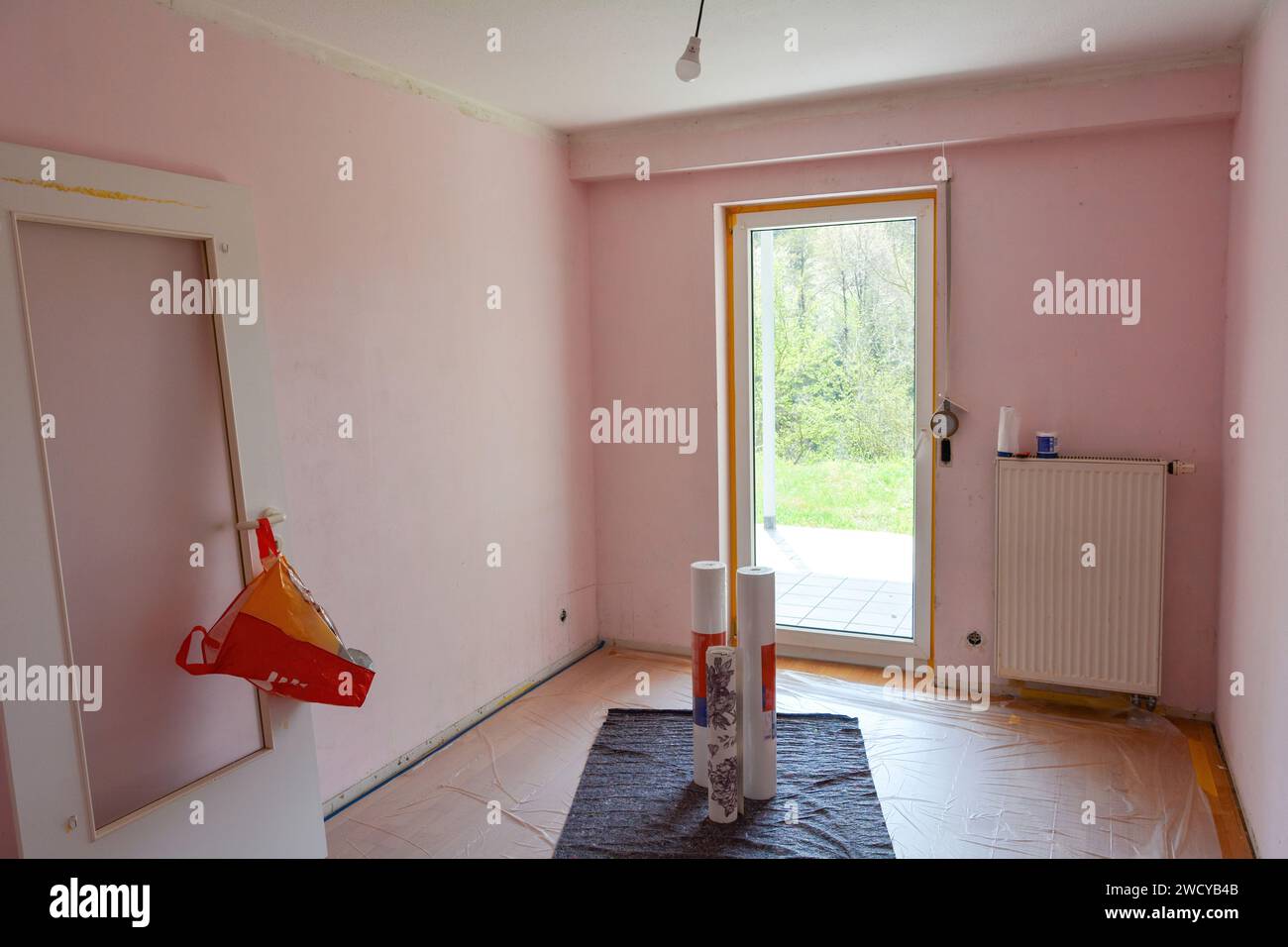 Pareti rosa con soffitto di un appartamento durante i lavori di ristrutturazione, porte sospese a parete, con finestra in camera Foto Stock