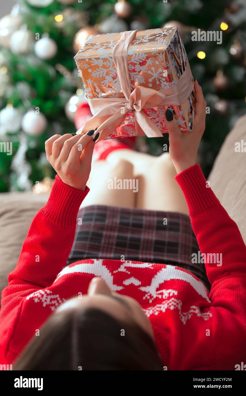 Ragazza in maglione rosso con un regalo sullo sfondo dell'albero di Natale Foto Stock
