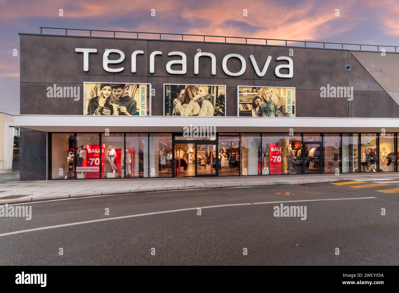 Savigliano, Italia - gennaio 2024: Grande negozio di abbigliamento Terranova. Vista del tramonto sulla facciata esterna con grandi finestre illuminate con grande logo si Foto Stock