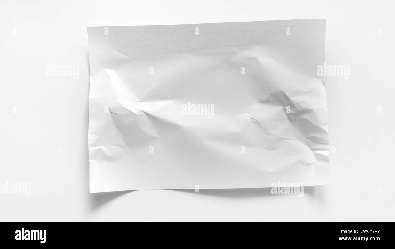 Un foglio A4 bianco leggermente stropicciato si trova su uno sfondo bianco. Mockup per iscrizioni, parole, pubblicità con spazio di copia. Foglio bianco stropicciato di Foto Stock