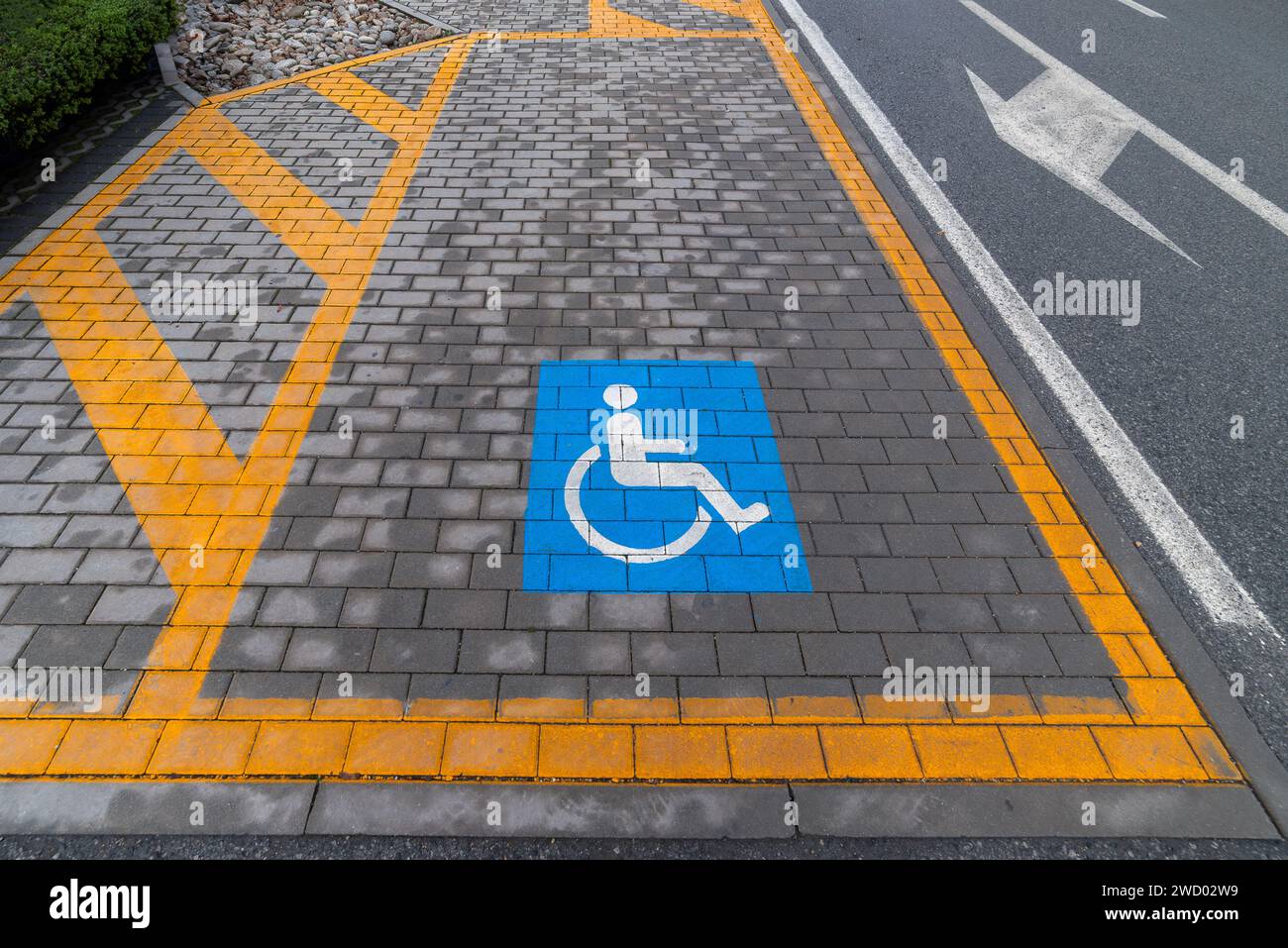 Parcheggio per disabili contrassegnato da linee gialle e dal simbolo blu di disabilità in un parcheggio. Foto Stock