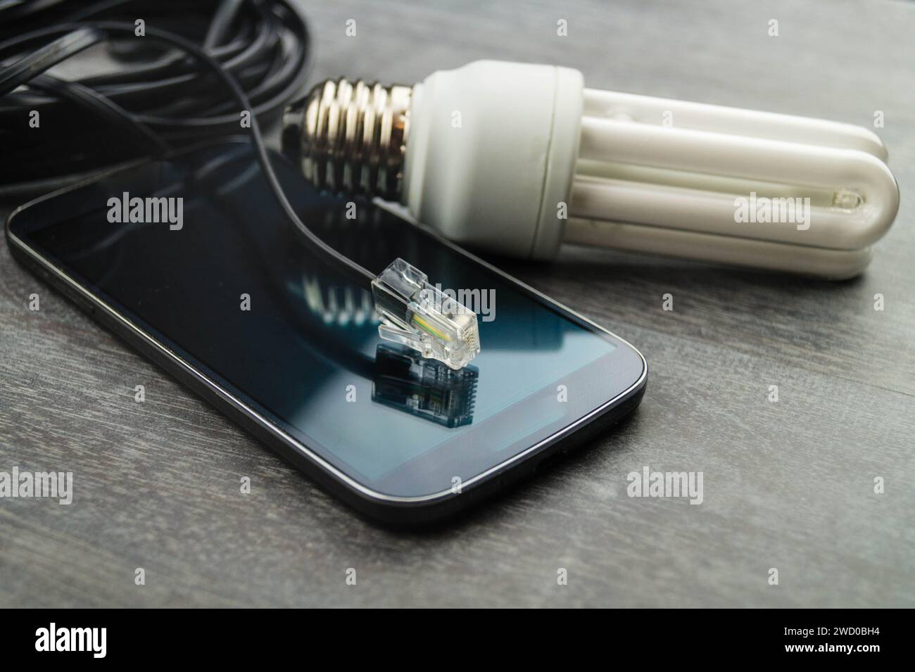 Lampada a risparmio energetico, smartphone e spina di rete, immagine simbolica per la casa intelligente Foto Stock