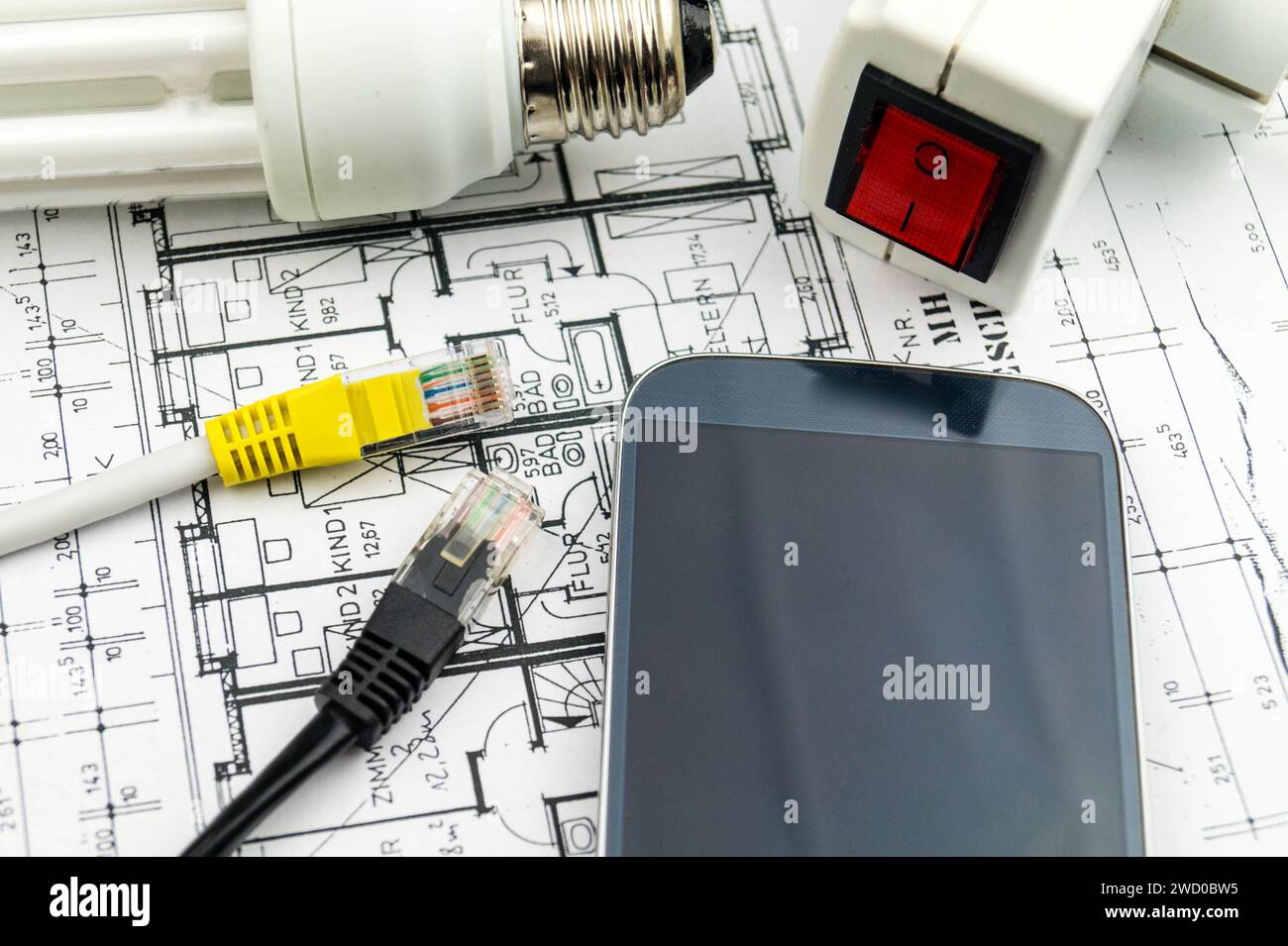 Lampada a risparmio energetico, smartphone e spina di rete sui disegni di costruzione, immagine simbolica per la casa intelligente Foto Stock