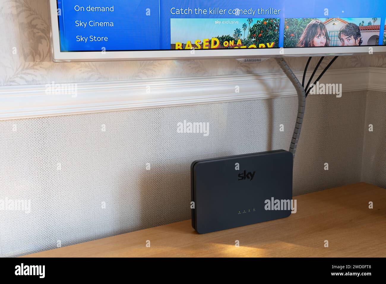 Un hub router Sky Broadband Q sotto uno smart TV che mostra la home page di Sky TV, Inghilterra. Concetto: Provider di servizi Internet del Regno Unito Foto Stock