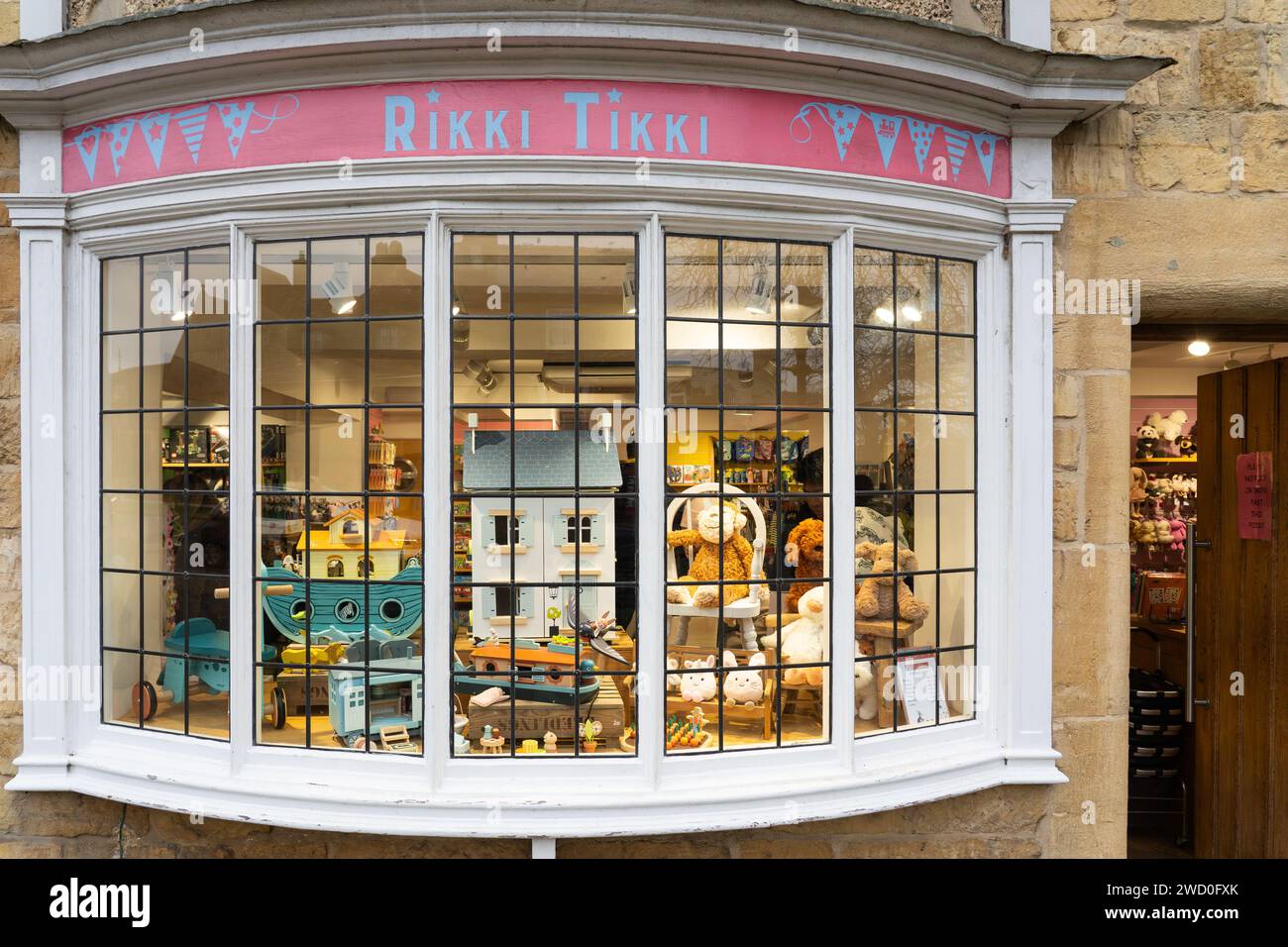 Guardando la finestra di un negozio di giocattoli. Occupando il "vecchio ufficio postale" al 25 di High Street, Broadway, Rikki Tikki è un vivace e colorato negozio di giocattoli. REGNO UNITO Foto Stock