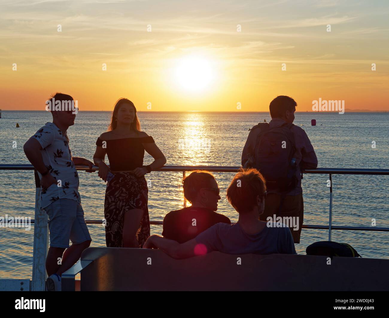 Persone in silhouette che guardano uno spettacolare tramonto rosso vivo da St Kilda Beach, Melbourne, Australia Foto Stock