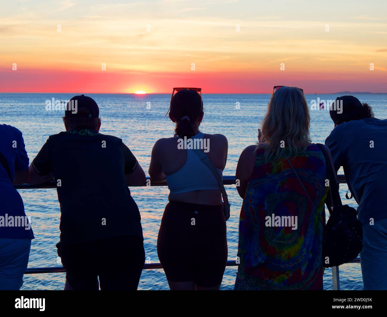 Persone in silhouette che guardano uno spettacolare tramonto rosso vivo da St Kilda Beach, Melbourne, Australia Foto Stock