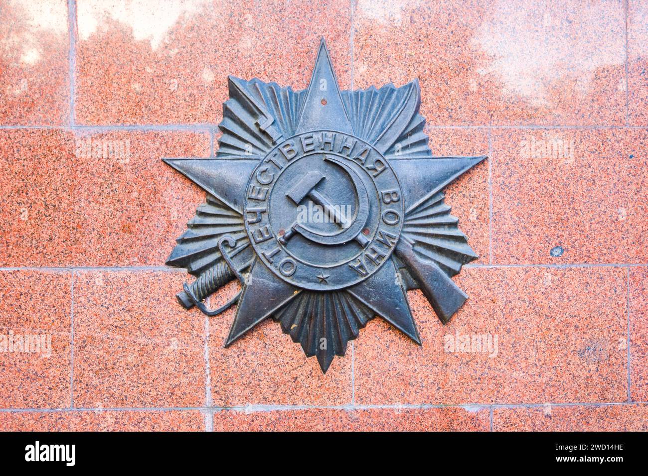 Uno stemma con martello e falce con spada e fucile, che rappresenta la seconda guerra mondiale, la grande guerra patriottica. Al Parco Panfilov di Almaty, Kazakistan. Foto Stock