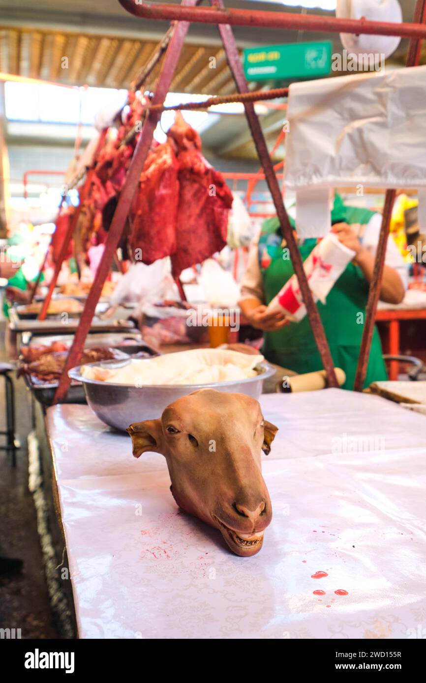 Al macellaio, sezione carne, un venditore, stalla con la testa di una pecora, capra. Presso il principale mercato alimentare locale dell'era sovietica, il Bazar verde. Ad Almaty, Foto Stock