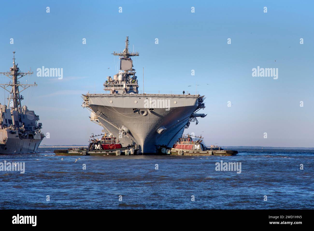 I rimorchiatori aiutano la nave d'assalto anfibio USS Kearsarge ad iniziare le prove in mare. Foto Stock