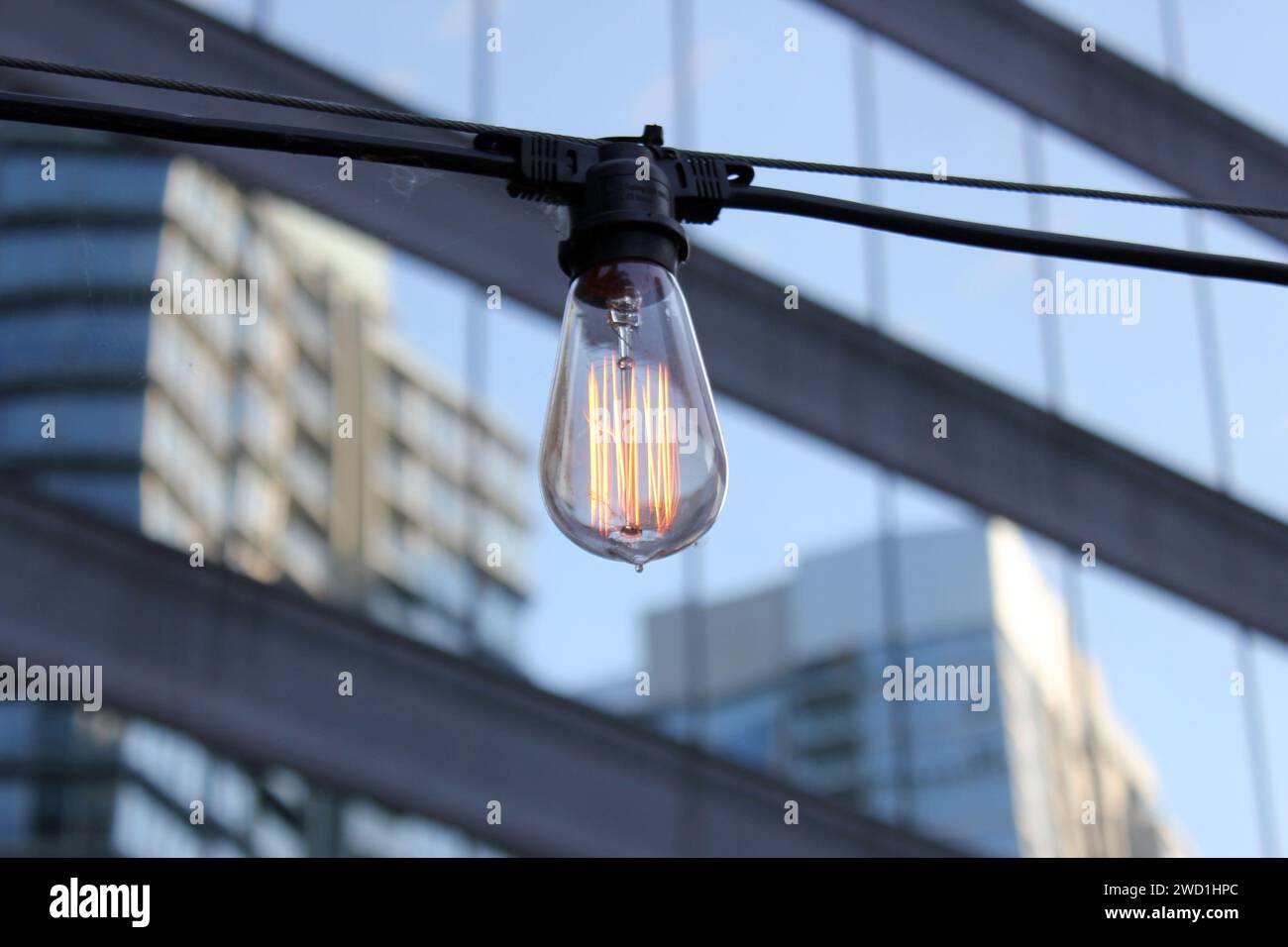 Una lampadina incandescente in mezzo a un paesaggio urbano con un edificio prominente sullo sfondo Foto Stock