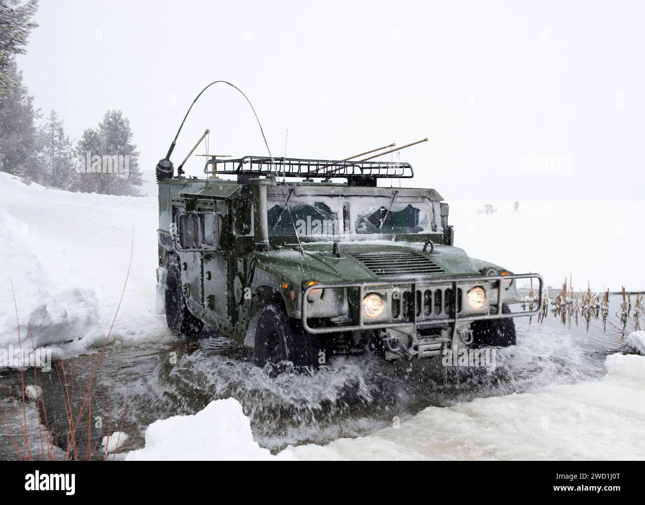 Un veicolo militare che attraversa un fiume in condizioni meteorologiche nevose. Foto Stock