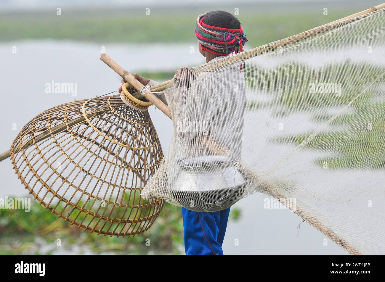 Le popolazioni rurali armate di trappole per pesci di bambù e reti da pesca artigianali prendono parte a una festa invernale di pesca bawa, che dura 100 anni, presso il Gowahori beel of Biswanath upazila a Sylhet. La gente del posto ha detto che il festival viene celebrato ogni anno nel primo giorno del mese di Bangla di Poush e, a parte la gente del posto, persone provenienti da diverse parti dell'Upozila si radunano al beel con diversi tipi di trappole da pesca per partecipare. Sylhet, Bangladesh. Foto Stock