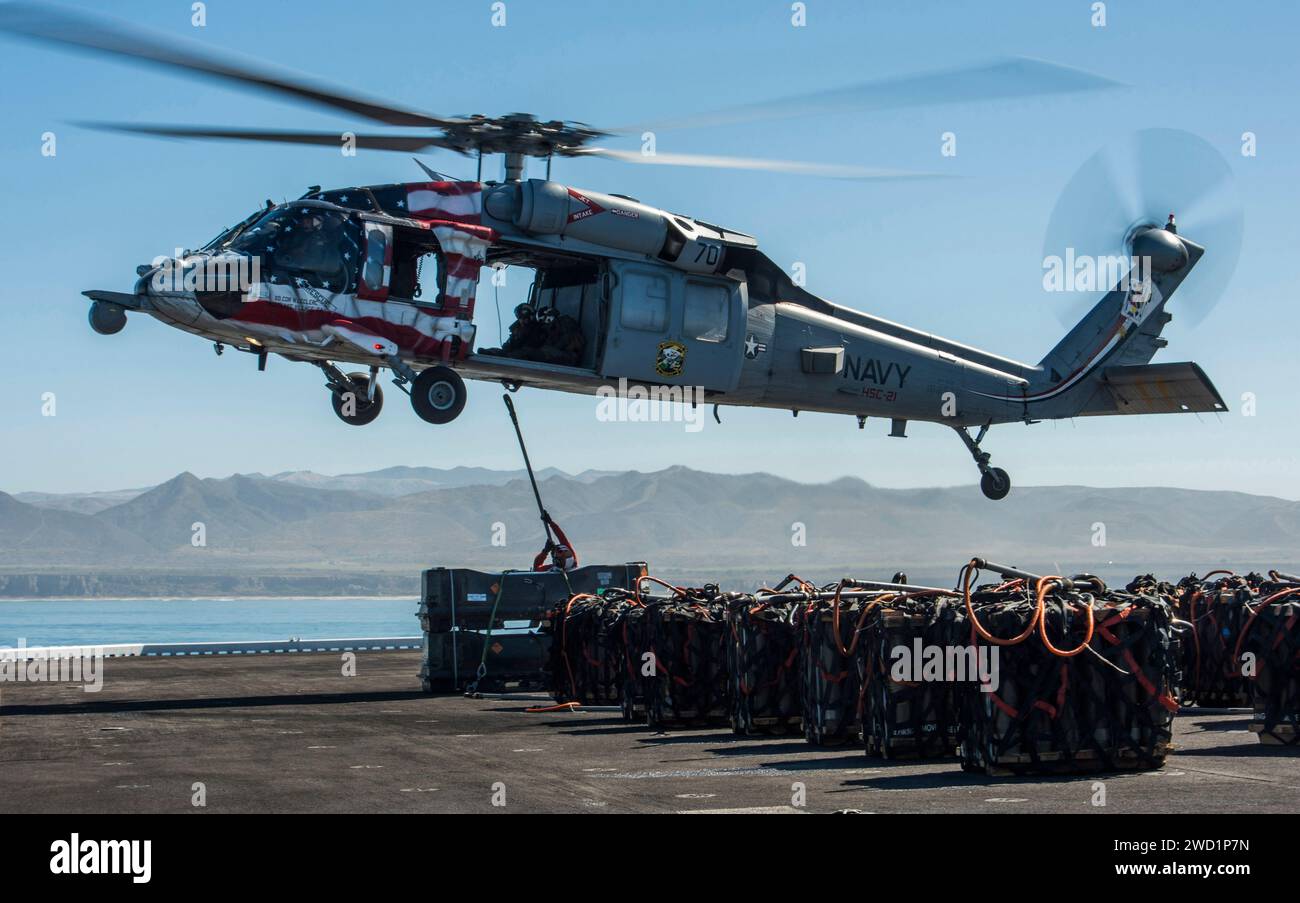 I marinai attaccano un pallet di ordigni a un MH-60S Sea Hawk a bordo dell'isola USS Makin. Foto Stock