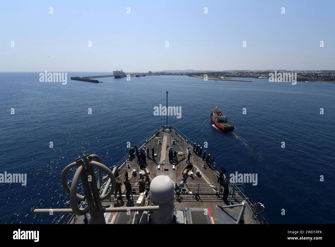 Un rimorchiatore greco assiste la nave da sbarco anfibio USS Carter Hall nel porto di Rodi, in Grecia. Foto Stock
