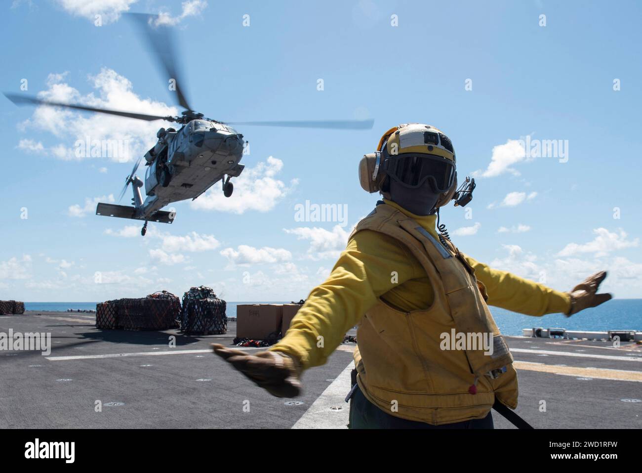 Aviation Boatswain's Mate segnala un elicottero MH-60S Sea Hawk sul ponte di volo della USS Bonhomme Richard. Foto Stock