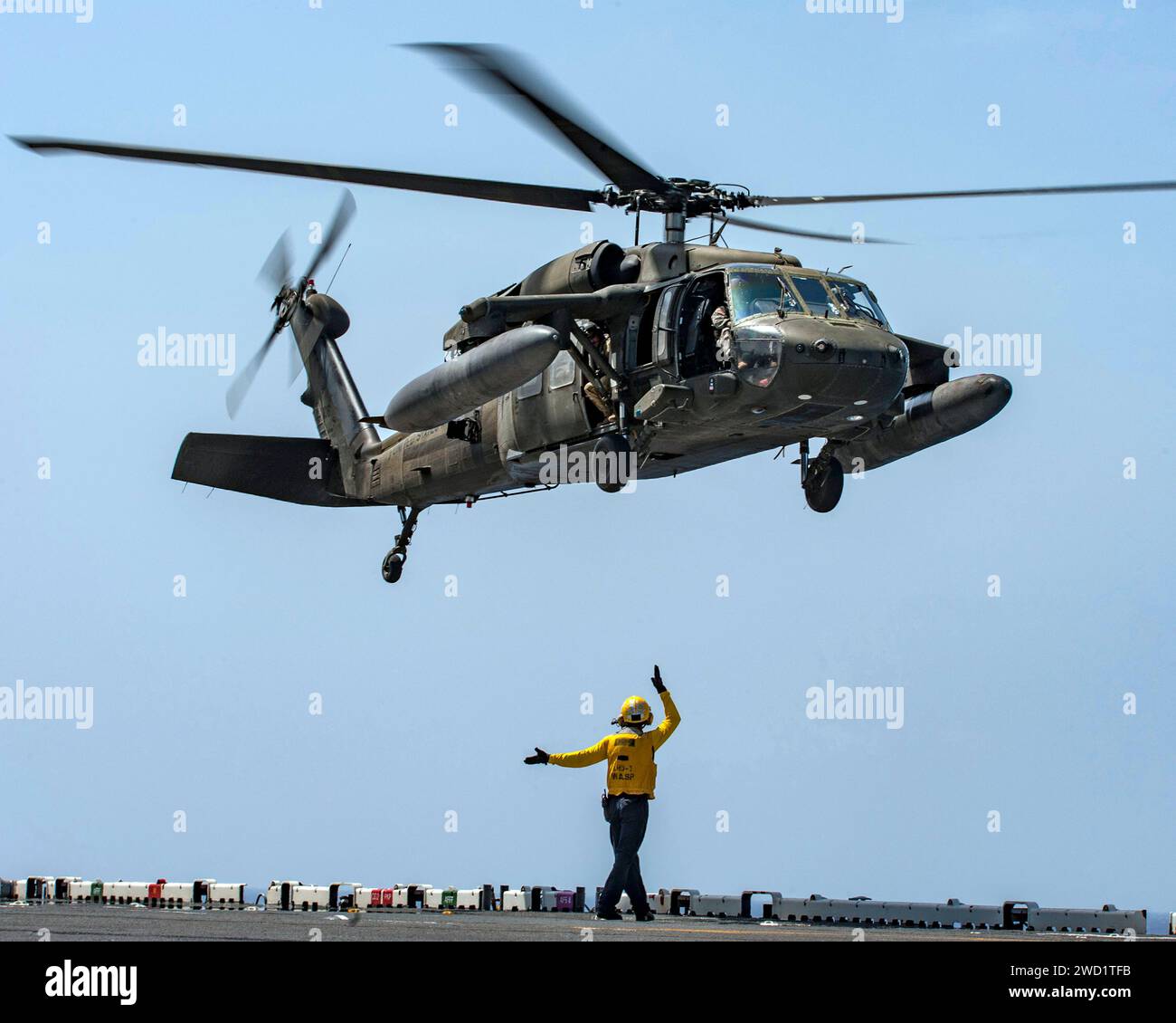 Un Sailor segnala il decollo di un elicottero UH-60 Black Hawk dell'esercito degli Stati Uniti dalla USS Wasp. Foto Stock
