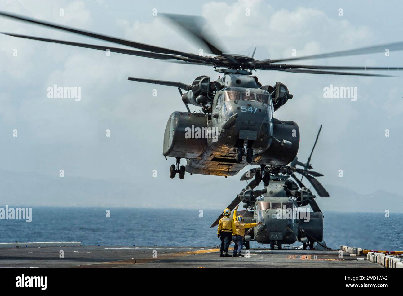 I marinai segnalano a un elicottero MH-53E Sea Dragon di decollare dalla USS Wasp. Foto Stock