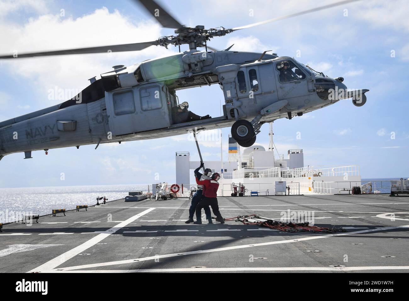 Un elicottero MH-60S Sea Hawk condisce un rifornimento in mare con il comfort dell'USNS. Foto Stock