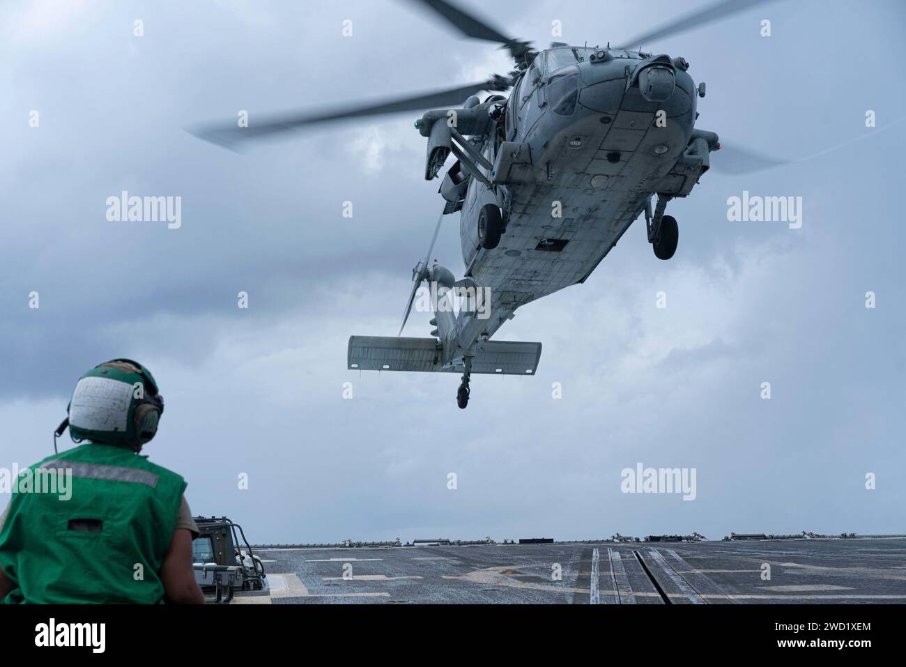 Aviation Electronics Mate osserva un MH-60S Sea Hawk mentre atterra sul ponte di volo della USS Halsey. Foto Stock