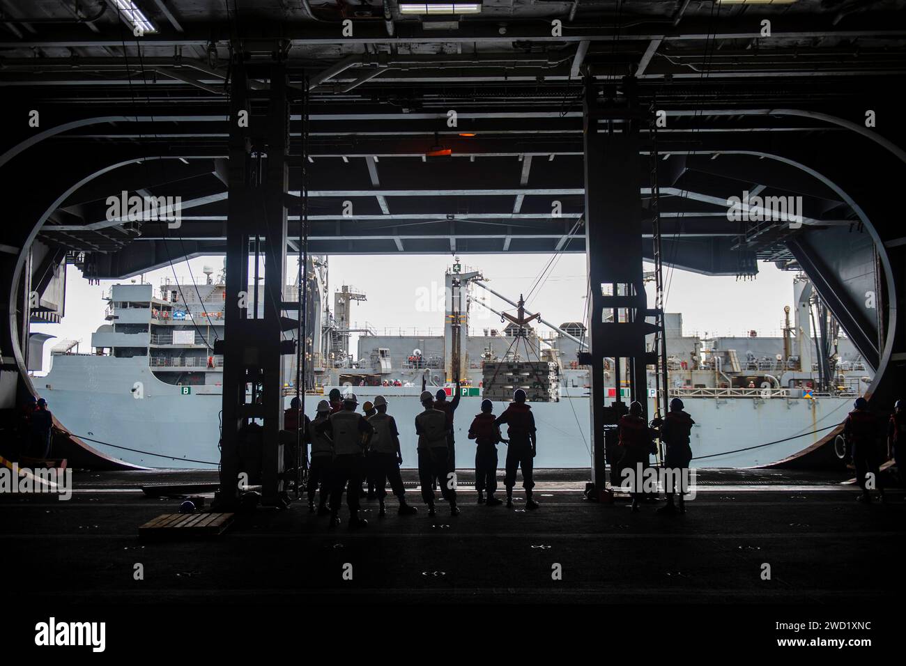 I marinai a bordo della USS Dwight D. Eisenhower ricevono ordigni dalla USNS Arctic durante un rifornimento in mare. Foto Stock