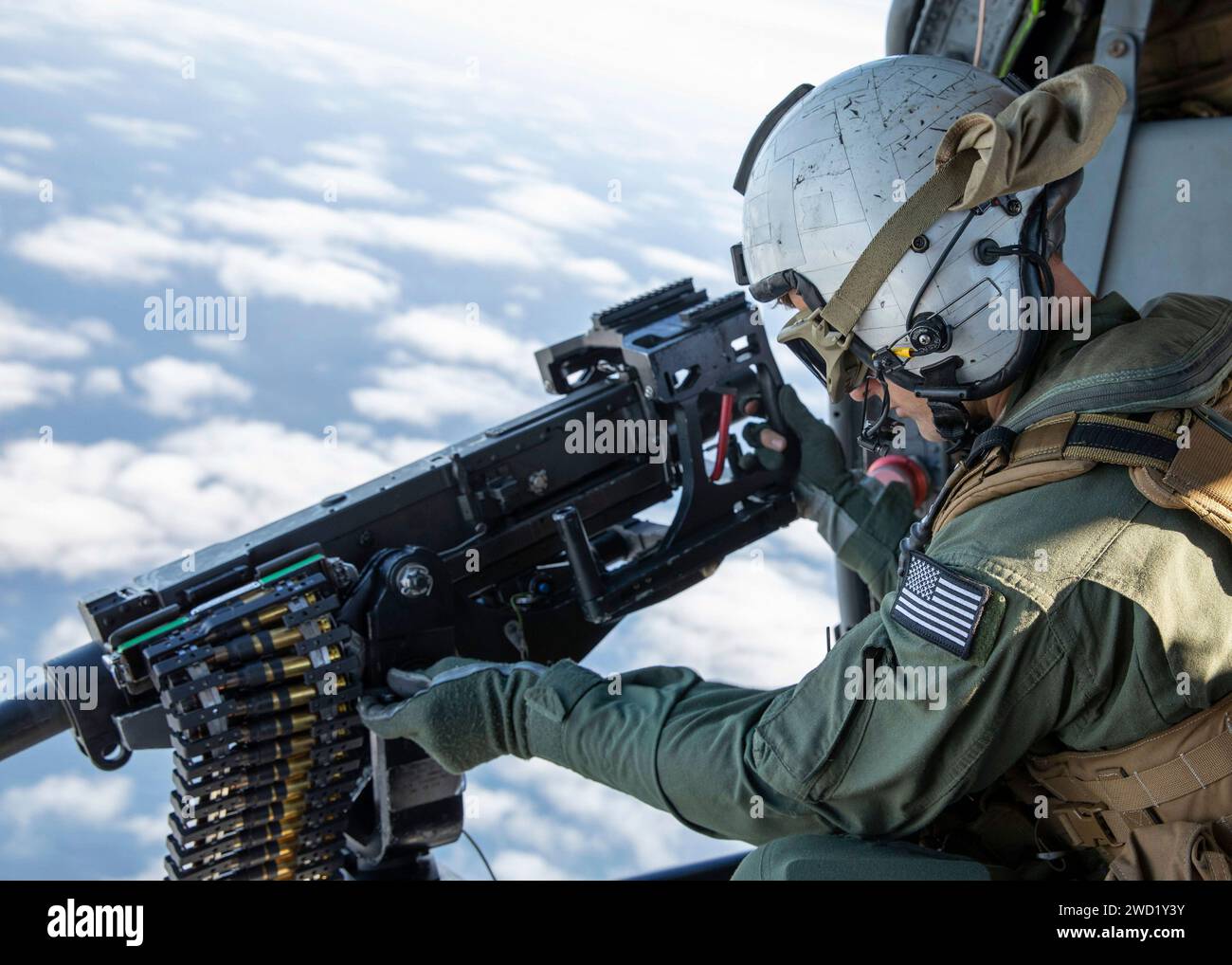 Naval Air Crewman regola una mitragliatrice calibro 50 su un elicottero MH-60S Sea Hawk. Foto Stock