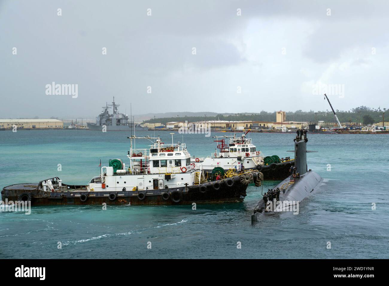I rimorchiatori trainano il sottomarino d'attacco della classe Rubis della marina francese FS Emeraude nel porto di Apra, Guam. Foto Stock