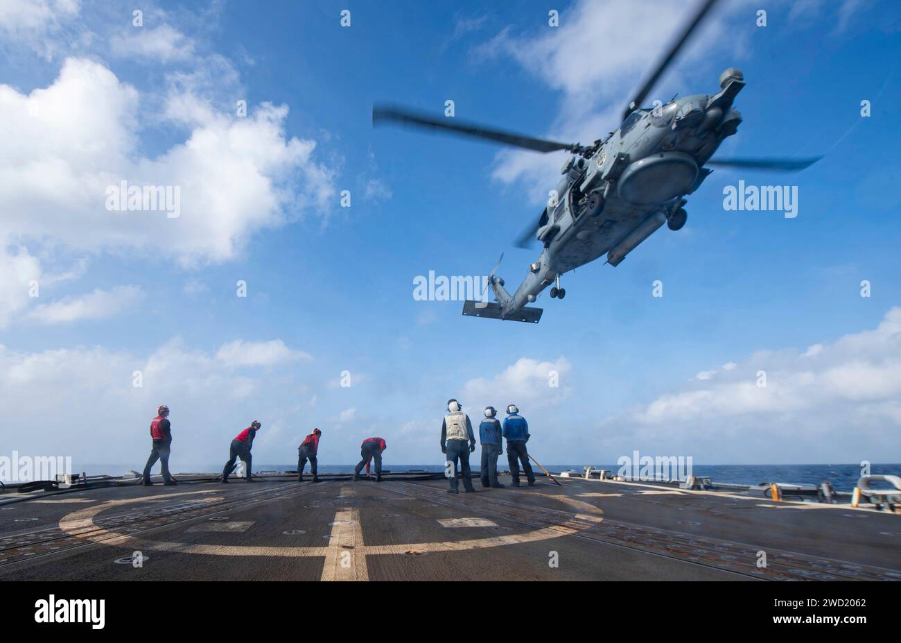 I marinai partecipano a un esercizio di rifornimento in elicottero con un MH-60S Sea Hawk a bordo della USS Sterett. Foto Stock