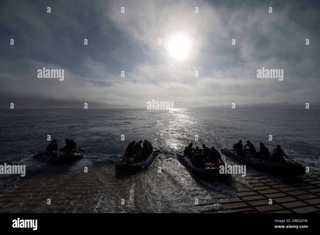 I marinai degli Stati Uniti lanciano armi da combattimento in gomma dal cancello di poppa dello USS Harpers Ferry. Foto Stock