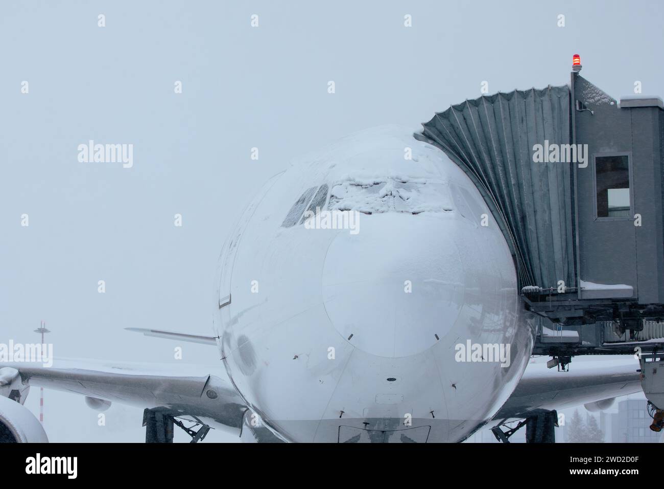 Aeroporto chiuso durante le forti nevicate. Aereo coperto di neve durante la gelida giornata invernale. Condizioni meteorologiche estreme durante il trasporto con spazio fotocopie. Foto Stock