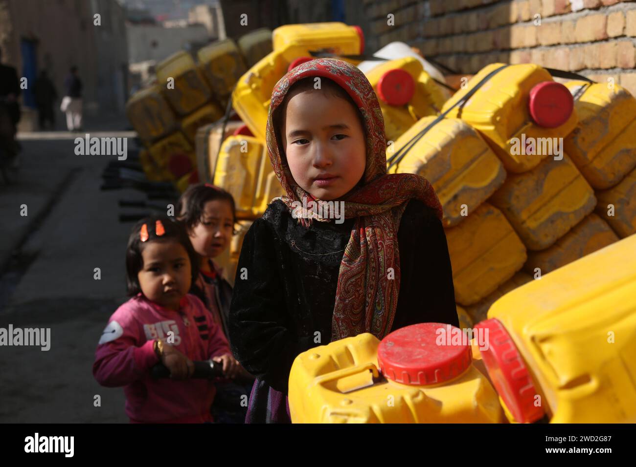 Kabul, Afghanistan. 11 gennaio 2024. I bambini si trovano accanto alle botti d'acqua a Kabul, capitale dell'Afghanistan, 11 gennaio 2024. PER ANDARE CON 'caratteristica: I residenti di Kabul colpiti dalla siccità che fanno la fila per ore per prendere l'acqua' credito: Saifurahman Safi/Xinhua/Alamy Live News Foto Stock