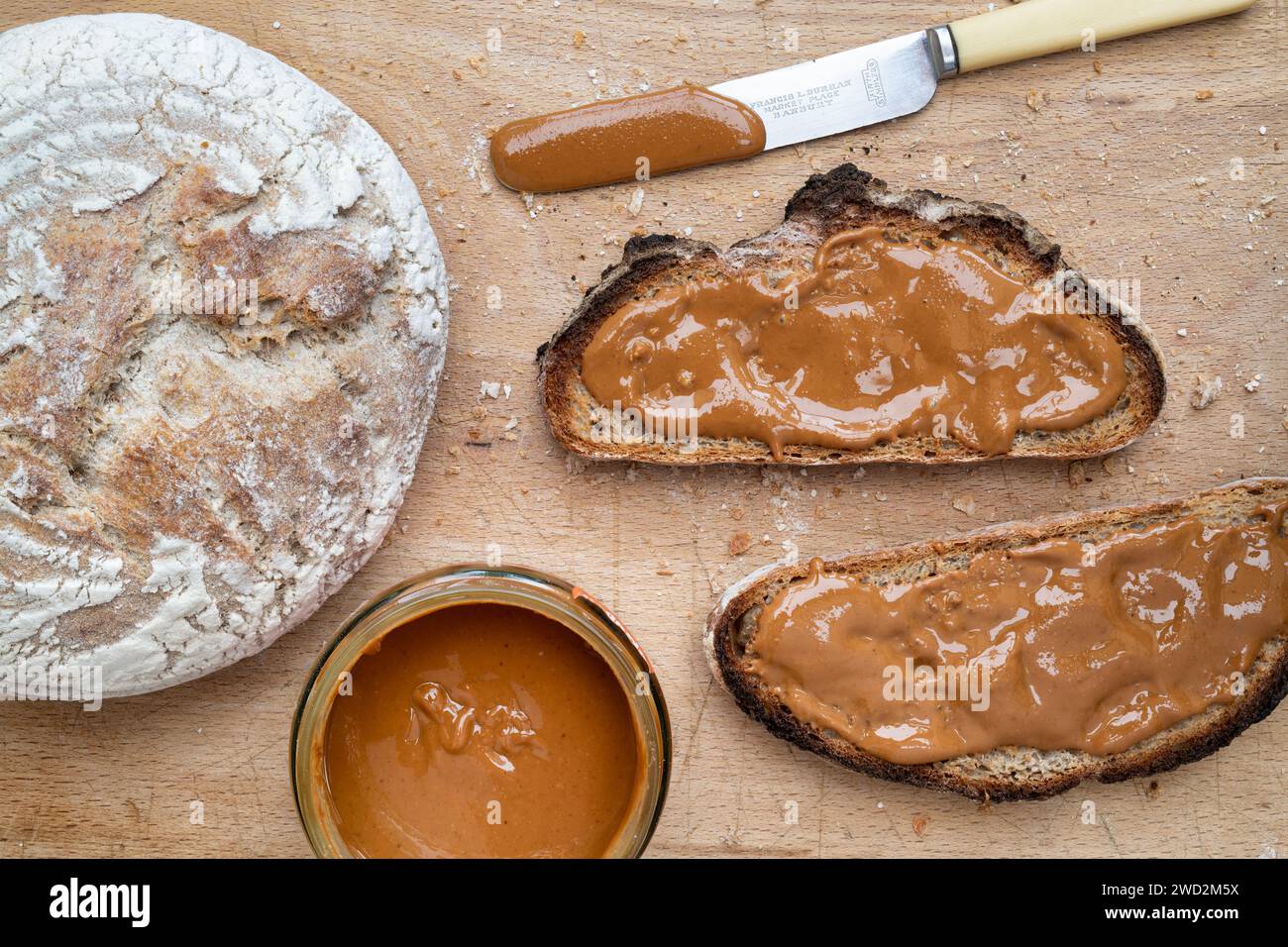 Lisciare il burro di arachidi sul pane tostato con lievito di origine Foto Stock