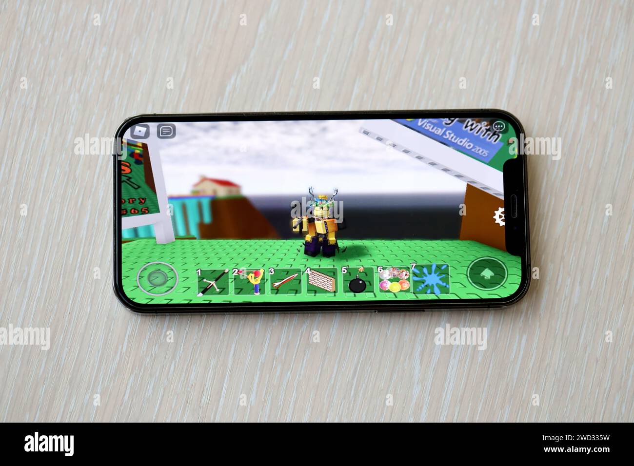 Roblox mobile iOS gioco su iPhone 15 schermo dello smartphone su un tavolo di legno durante il gioco mobile. Giochi e intrattenimento mobili su dispositivi portatili Foto Stock