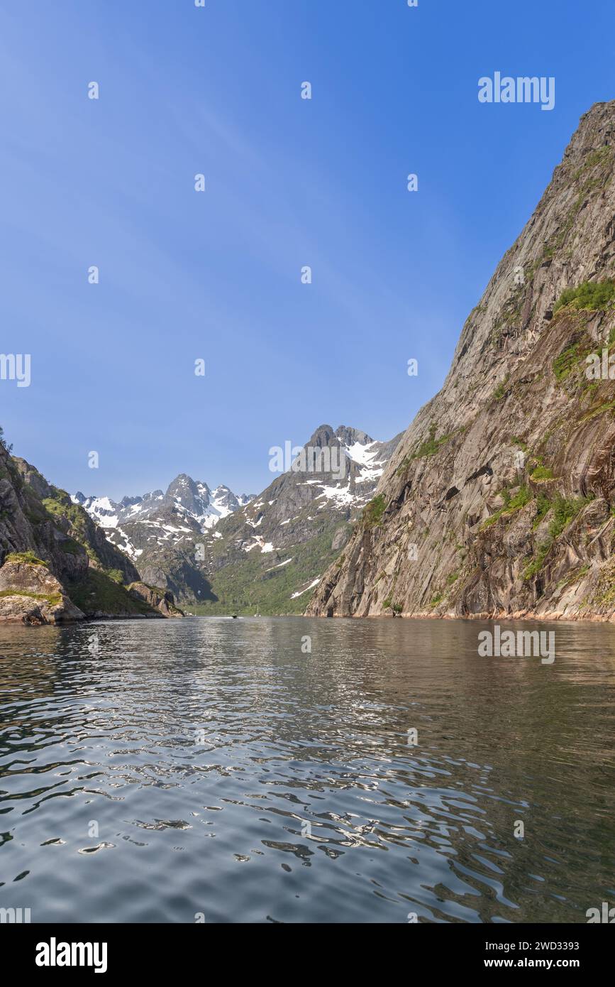 Nelle isole Lofoten, la grandiosità di Trollfjorden si dispiega con torreggianti pareti rocciose e montagne innevate che si riflettono Foto Stock