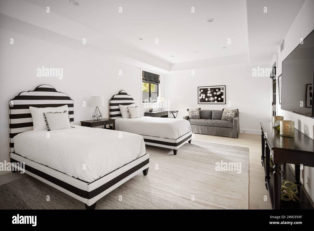Camera da letto con due letti e un grande televisore a schermo piatto Foto Stock