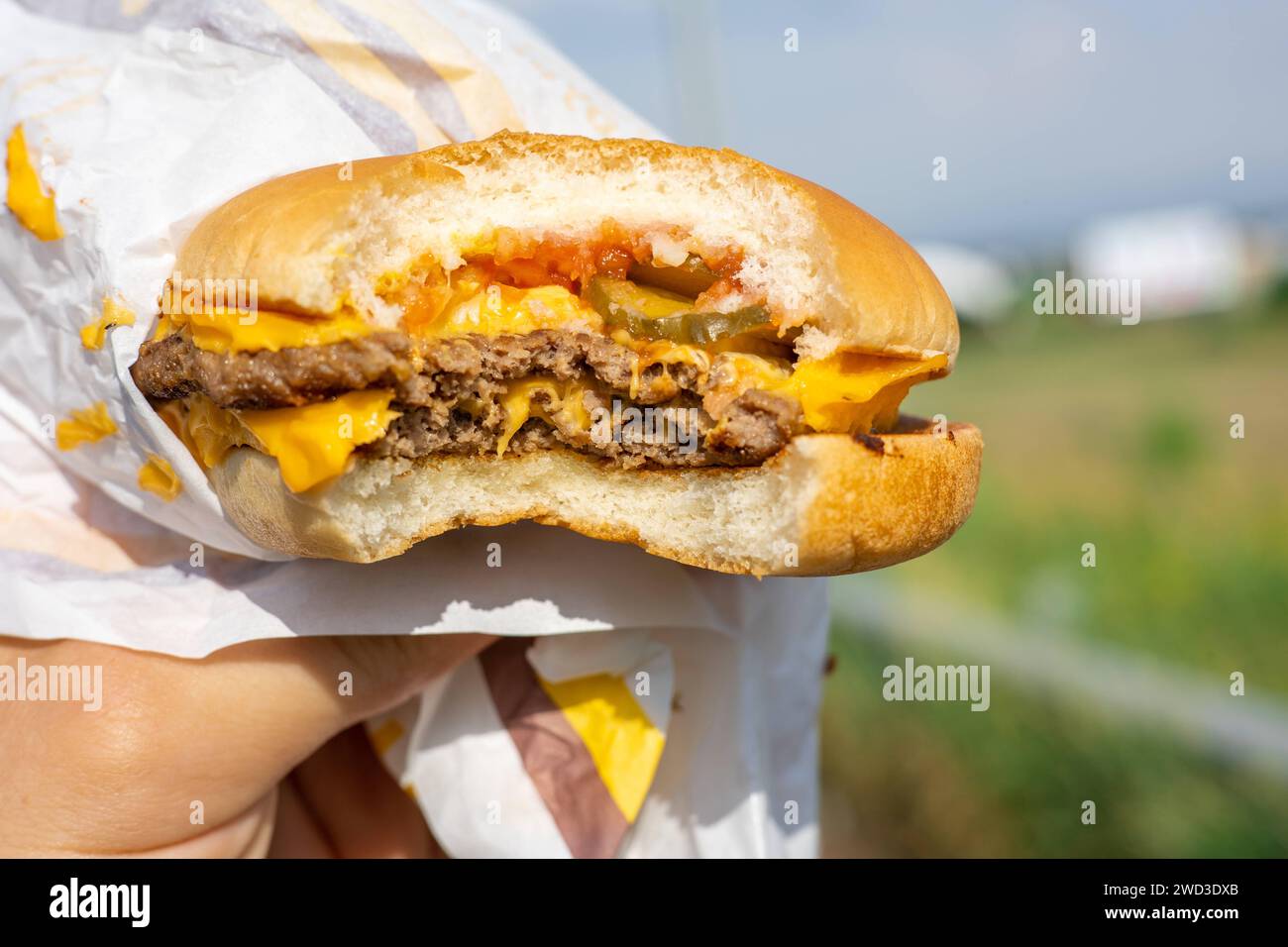 Il concetto di fast food e piatti da asporto. Grande hamburger succoso con formaggio in mano Copyright: XDmytroxNikolaienkox Foto Stock