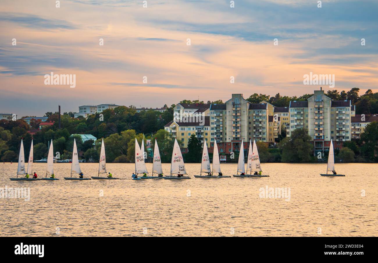 Barche a vela, barche a vela gommone, addestramento sul lago, al tramonto, in estate, a Stoccolma, Svezia, sul lago Mälaren. Parzialmente nuvoloso, arancione e rosa. Foto Stock