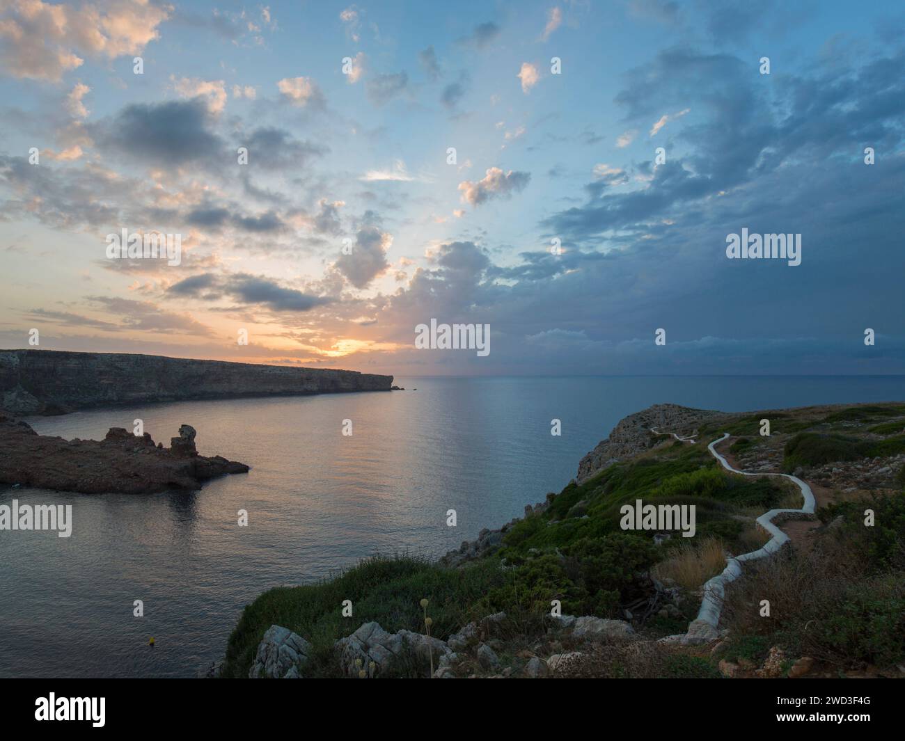 Cala Morell, Minorca, Isole Baleari, Spagna. Vista sul tranquillo Mar Mediterraneo fino a Punta de S'Escullar, tramonto. Foto Stock