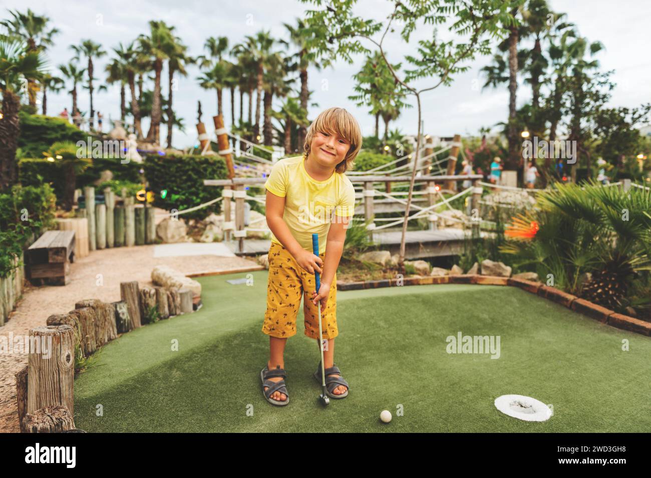 Divertente ragazzo che gioca a mini golf, bambino che ama le vacanze estive Foto Stock