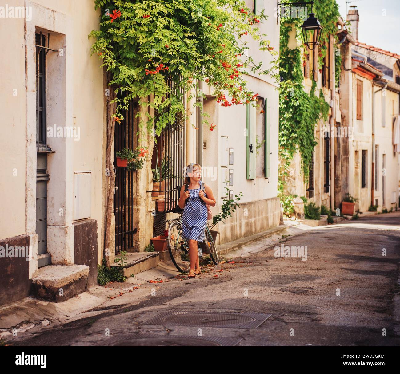 Ragazza carina turistica per le strade della Provenza, vestito di vichy blu, occhiali da sole e zaino. Concetto di viaggio con i bambini. Immagine acquisita Foto Stock