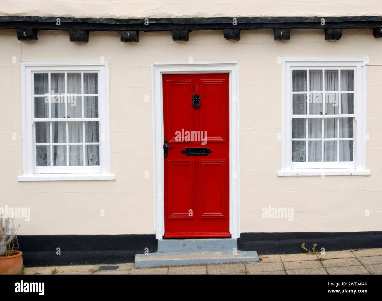 Parte di un antico edificio con una porta rossa brillante tra due finestre, Beccles, Suffolk, Inghilterra Foto Stock