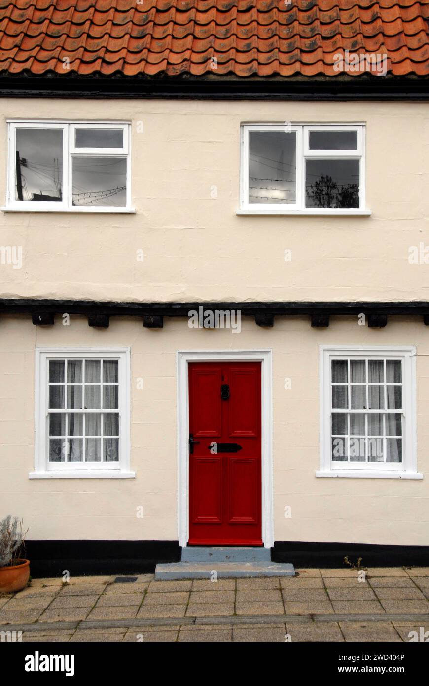 Parte di un antico edificio con una porta rossa brillante tra due finestre, Beccles, Suffolk, Inghilterra Foto Stock