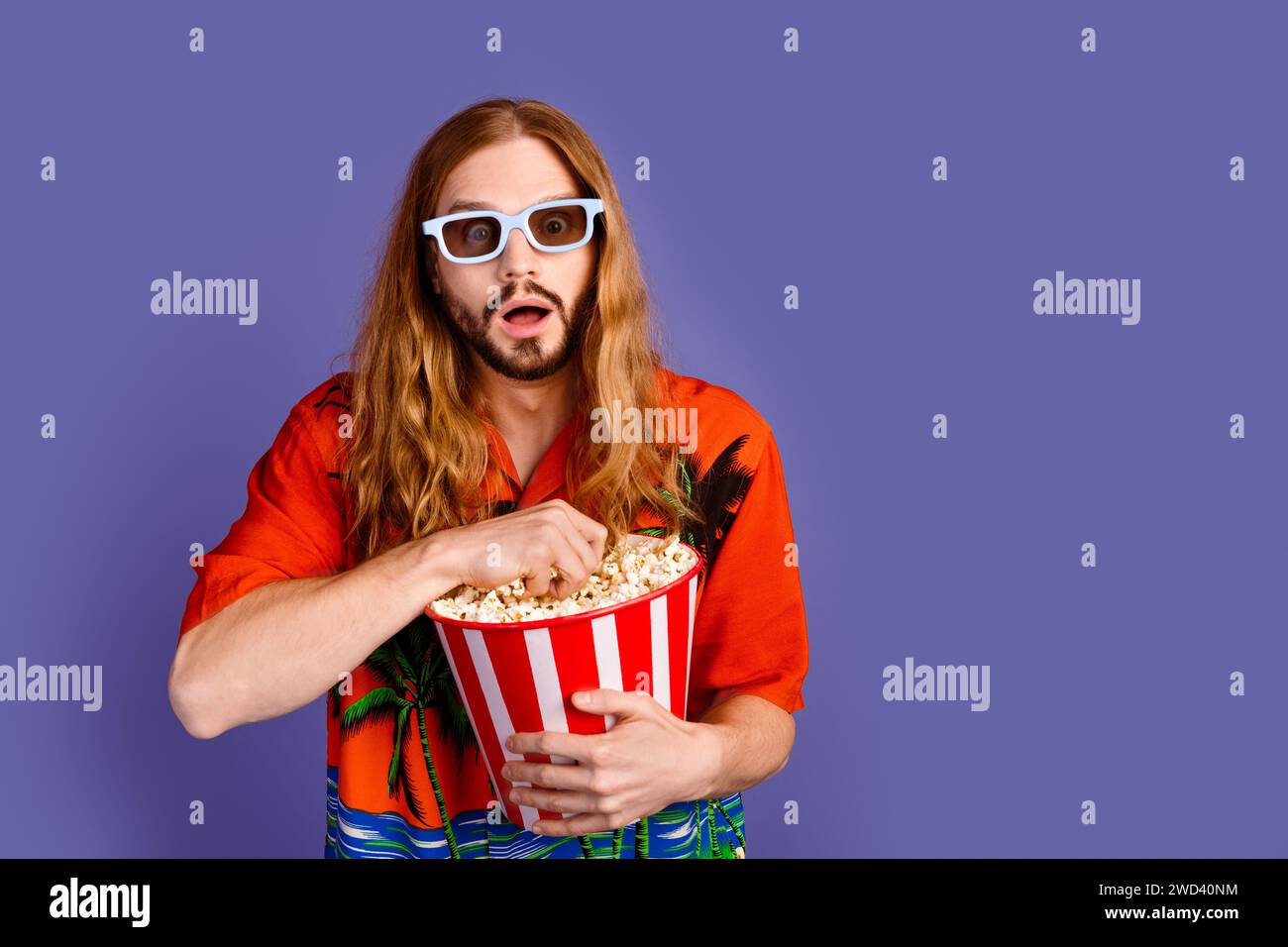 Foto di camicia uomo senza parole vestita con occhiali 3d mangiano popcorn fissando impressionanti effetti visivi isolati sullo sfondo di colore viola Foto Stock