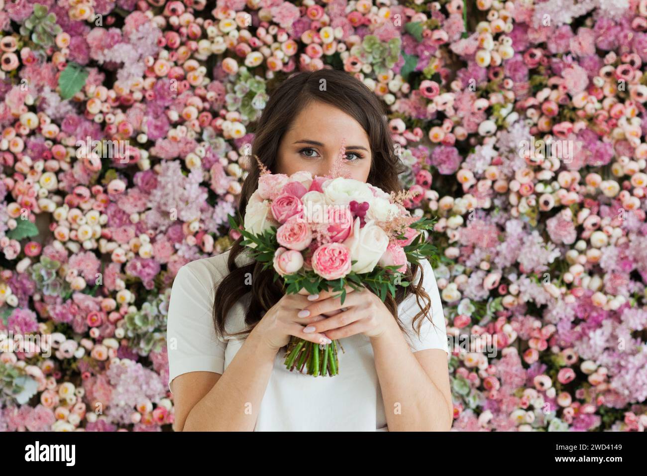 Bella donna sana sorridente e con bouquet di fiori di colore rosa colorato su sfondo floreale primavera o estate, ritratto di bellezza di moda da studio Foto Stock