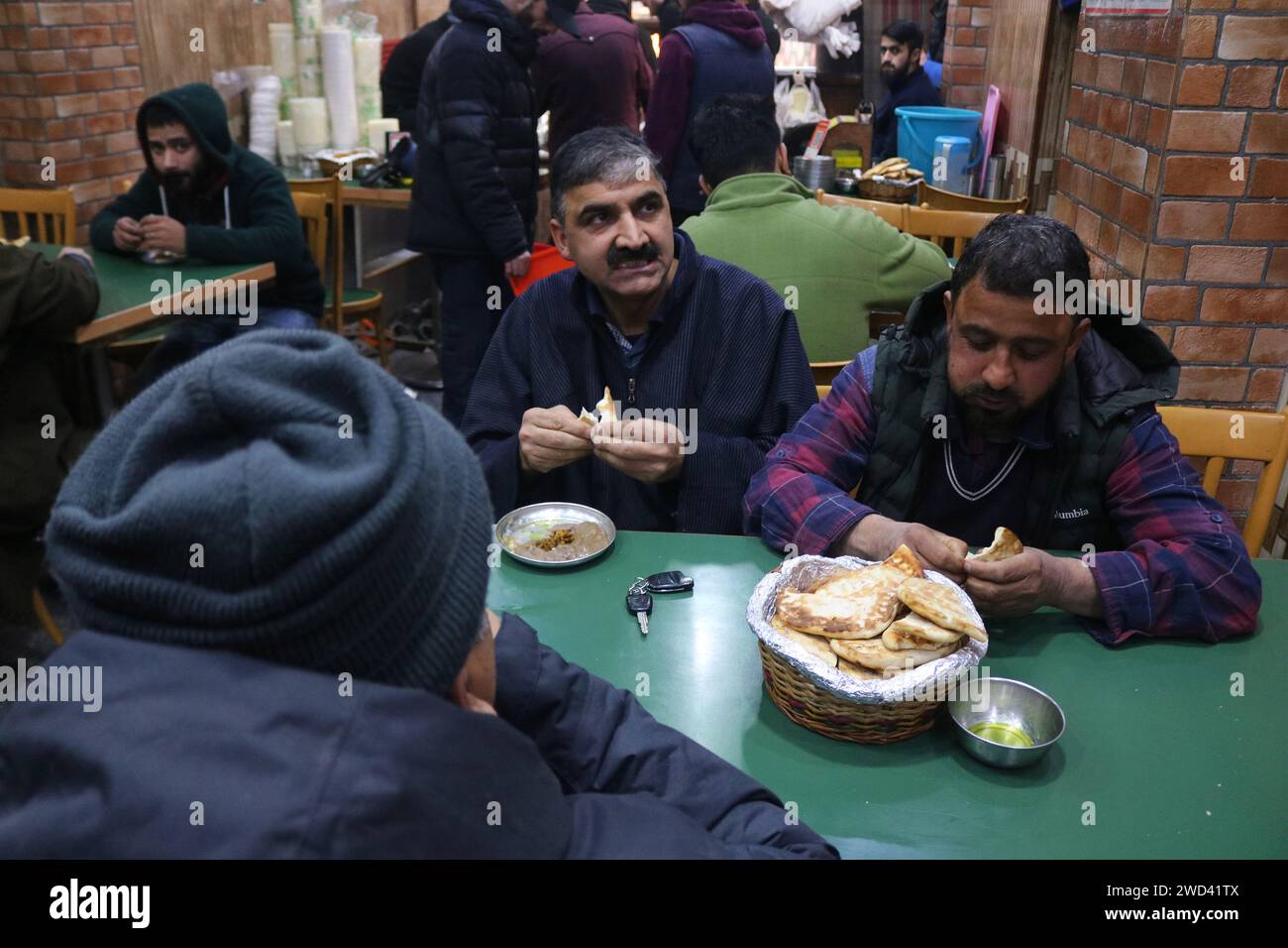 18 gennaio 2024, Srinagar Kashmir, India: I clienti mangiano Harissa (cibo tradizionale Kashmiri) in una mattinata fredda a Srinagar. L'Harissa è una ricetta unica di montoni antichi, preparata durante gli inverni del Kashmir. È principalmente disponibile nelle ore del mattino a base di montone, specialmente di pecore. La montone viene prima cotta a temperatura mite e tutte le ossa vengono estratte per renderla disossata. Il montone viene quindi mescolato con farina di riso, acqua e spezie varie e viene mescolato costantemente fino a diventare squashy. La gente apprezza soprattutto questo piatto con pane al forno. Il 18 gennaio 2024, Srinagar Kashmir, India. (Foto Foto Stock