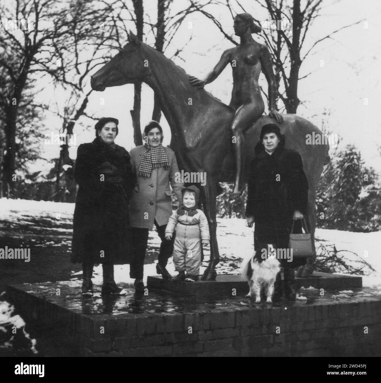 Una foto antica mostra un gruppo di donne con un bambino davanti a una scultura raffigurante una donna a cavallo. Amburgo, Germania. . 14 gennaio 1960. Foto Stock